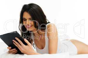 young woman reading a tablet on the bed
