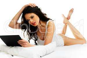beautiful woman relaxing on her bed with a tablet