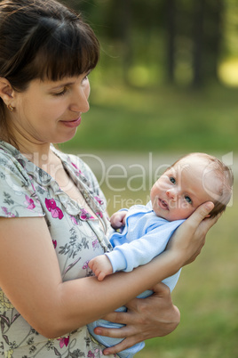 Cute little newborn baby child on mother hands walking outdoor