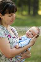 Cute little newborn baby child on mother hands walking outdoor