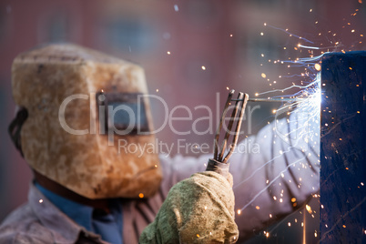 Arc welder worker in protective mask welding metal construction