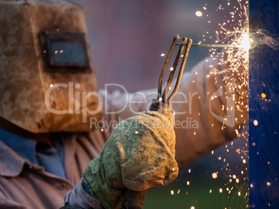 Arc welder worker in protective mask welding metal construction