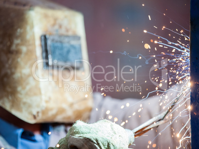 Arc welder worker in protective mask welding metal construction