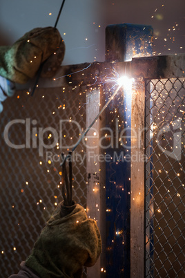 Arc welder worker in protective mask welding metal construction