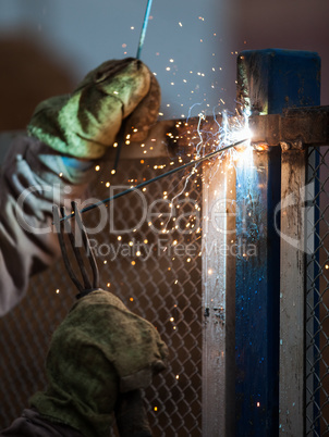 Arc welder worker in protective mask welding metal construction
