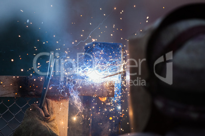 Arc welder worker in protective mask welding metal construction