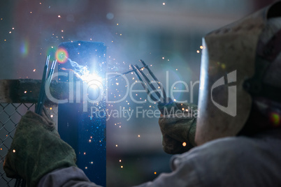 Arc welder worker in protective mask welding metal construction