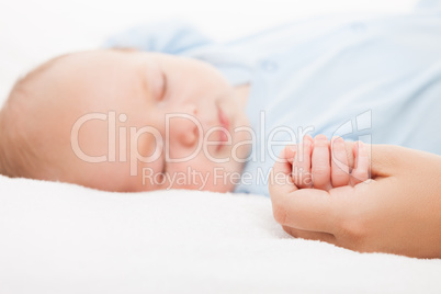 Cute sleeping newborn baby child holding mother hand