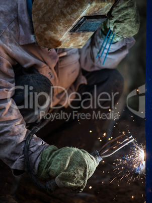 Arc welder worker in protective mask welding metal construction