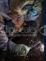 Arc welder worker in protective mask welding metal construction
