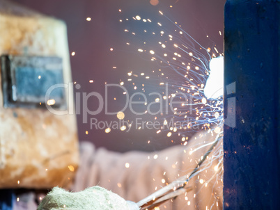 Arc welder worker in protective mask welding metal construction