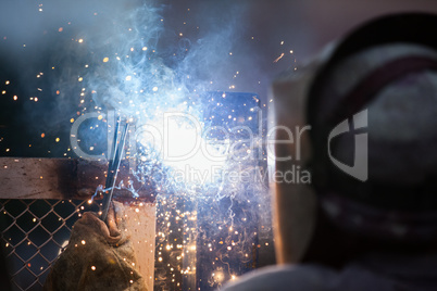 Arc welder worker in protective mask welding metal construction