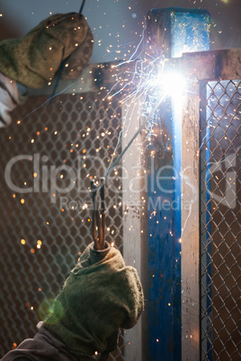 Arc welder worker in protective mask welding metal construction