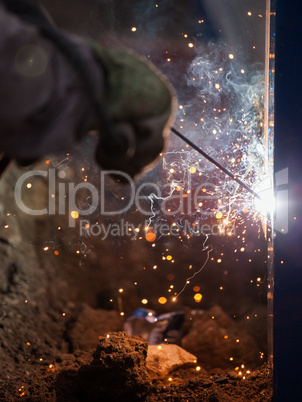 Arc welder worker in protective mask welding metal construction