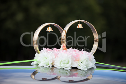Gold rings and rose flowers on wedding car