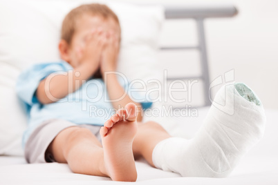 Little child boy with plaster bandage on leg heel fracture or br