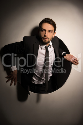 businessman climbing out of a circular hole