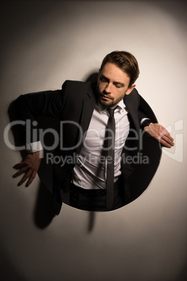businessman climbing out of a circular hole