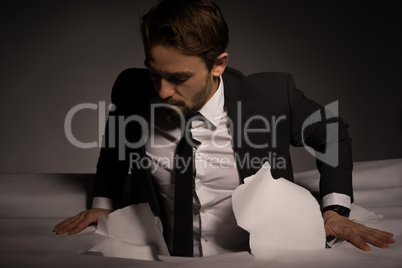 handsome young bearded businessman climbing out of a hole