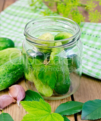 Cucumbers in a jar with leaves and napkin