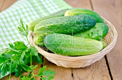 Cucumbers with parsley in wicker basket on a board
