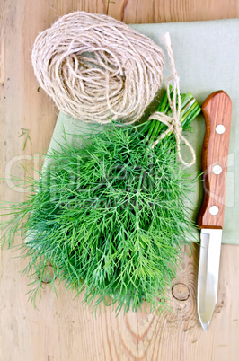 Dill with a knife and twine on the board