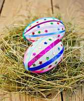 Easter eggs with ribbons and sequins in the hay