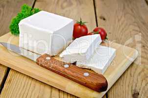 Feta cheese on the board with tomatoes and parsley