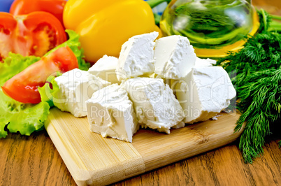 Feta cheese on the board with vegetables and salad