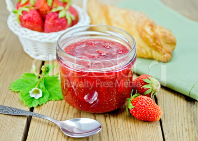 Jam of strawberry with a bun on the board