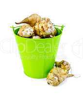 Jerusalem artichokes in a green bucket and on the table