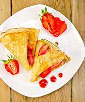 Pancakes with strawberries and jam on plate and board