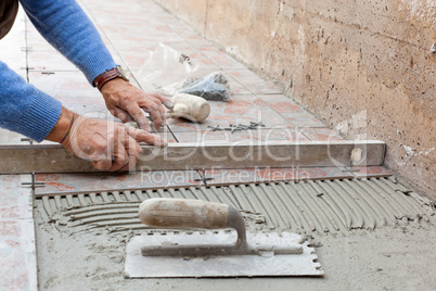 Worker leveling new pavement with a specific tool