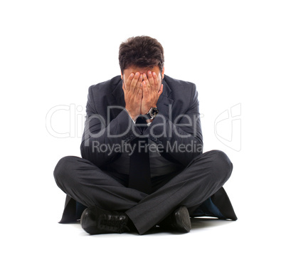 Depressed young businessman sitting on the ground