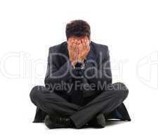 Depressed young businessman sitting on the ground