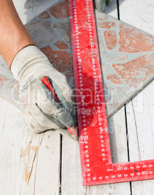 Man measuring a tile piece with a pencil