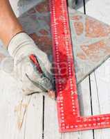 Man measuring a tile piece with a pencil