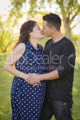 Hispanic Man Kisses His Pregnant Wife Outdoors At the Park