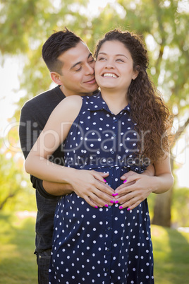 Hispanic Man Hugs His Pregnant Wife Outdoors At the Park
