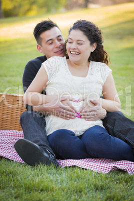 Pregnant Hispanic Couple Making Heart Shape with Hands on Belly