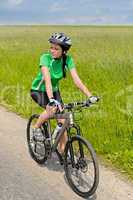 Woman biking on countryside road sunny day