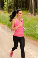 sportive woman running through forest