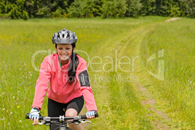 Woman riding bicycle on meadow path
