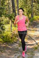 athlete woman running through forest training