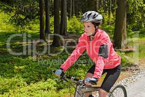 Woman mountain biking in forest sunny day