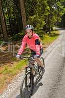 woman mountain biking in sunny forest smiling
