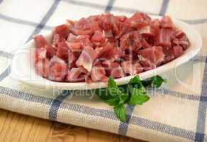 Serrano ham  diced for cooking on a white dish