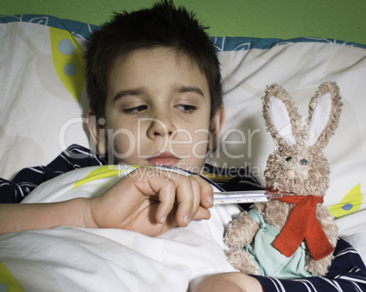 Sick child in bed with teddy bear