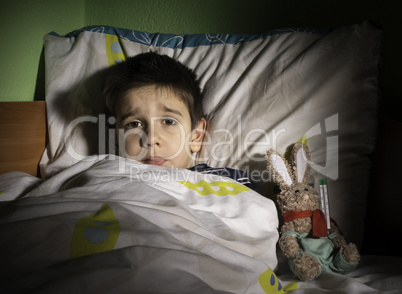 Sick child in bed with teddy bear