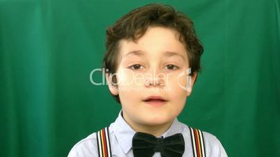 Little boy talking to a camera in front of a green screen